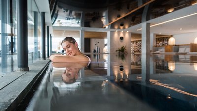 Donna rilassata a bordo piscina interna in zona benessere moderna