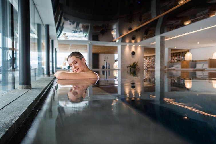 Donna rilassata a bordo piscina interna in zona benessere moderna