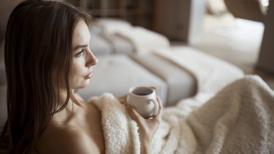 Donna rilassata sul divano con coperta che tiene una tazza di tè