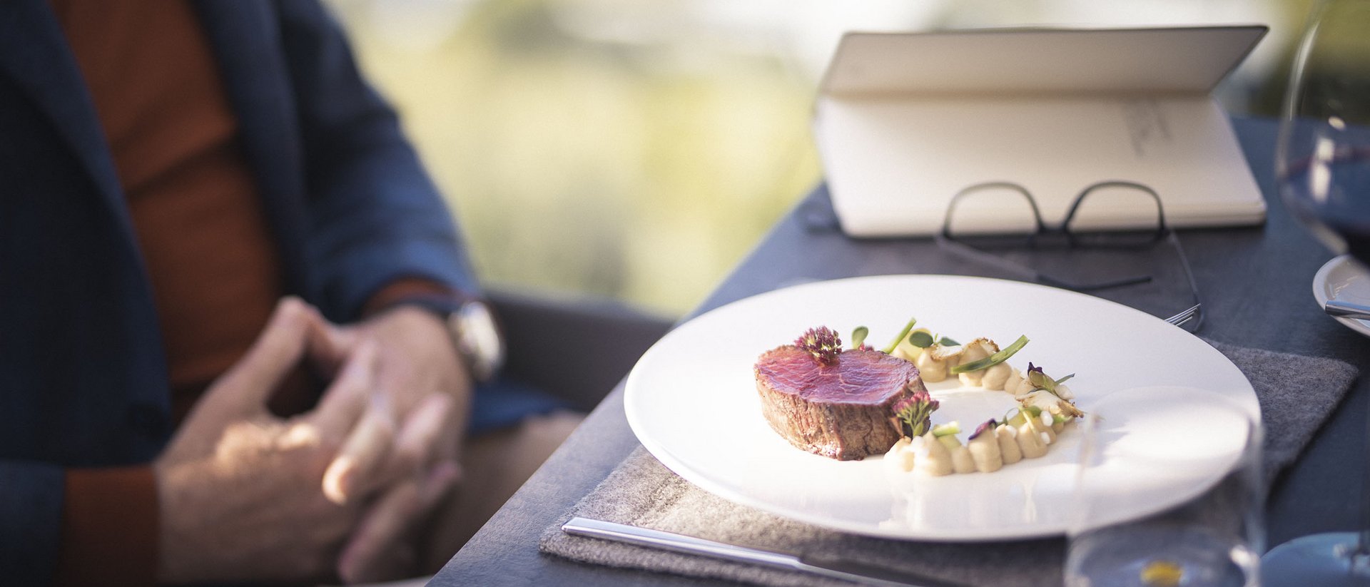Set table with fine meat dish and person blurred in the background