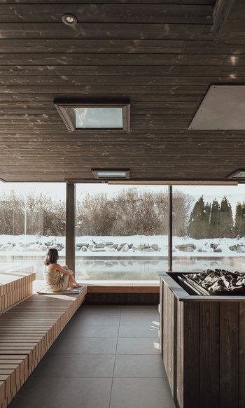 Die Heimat des Strahlens: Ihr Wellnesshotel in Südtirol Frau entspannt in Sauna mit Blick auf schneebedeckte Landschaft
