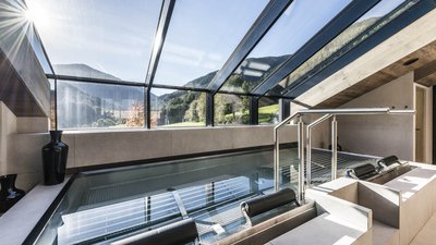 Piscina interna moderna con tetto in vetro e vista sulle montagne