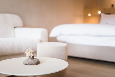 Modern side table with vase in front of sofa and bed in neutral room