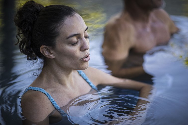 Donna rilassata nell'acqua che chiude gli occhi e respira profondamente