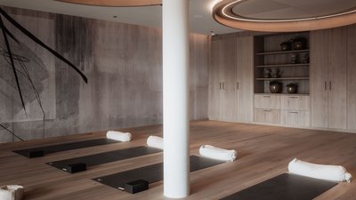 Moderner Yoga-Raum mit Matten und Kissen auf Holzboden und indirekter Deckenbeleuchtung
