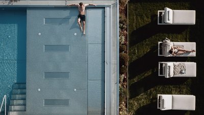 Photos from your hotel in Pfalzen in Val Pusteria/Pustertal Aerial view of a man at the pool and a woman lying on a lounge chair in the garden