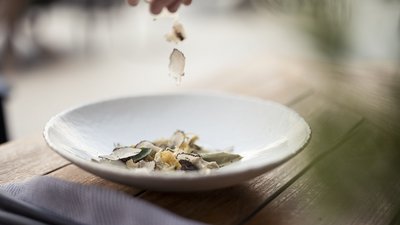 L’esclusività in foto: il nostro chalet in Alto Adige di lusso Mano che sparge scaglie di tartufo su un piatto bianco con cibo