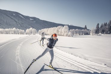 Due sciatori di fondo su pista appena preparata in una giornata invernale soleggiata
