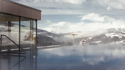 Photos from your hotel in Pfalzen in Val Pusteria/Pustertal Steaming outdoor pool with mountain view and modern glass building under cloudy sky