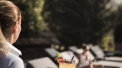 Cameriera porta cocktail su vassoio a persona sdraiata su lettino all'aperto