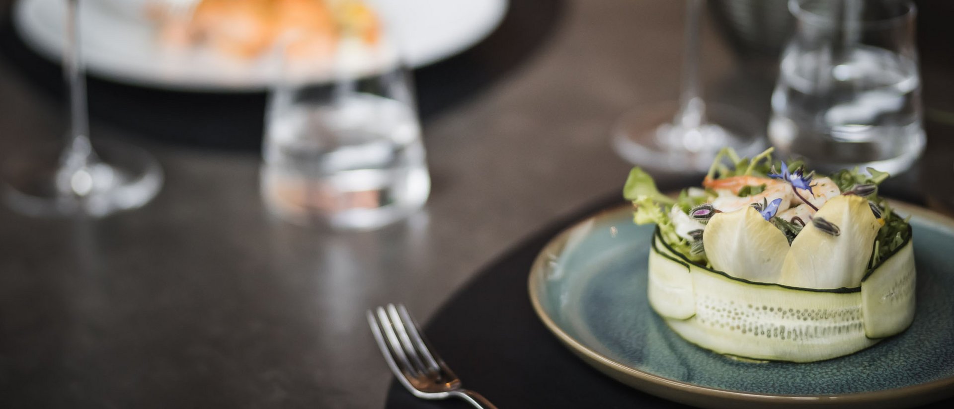 Insalata ben presentata su un piatto con bicchiere di vino e acqua sullo sfondo