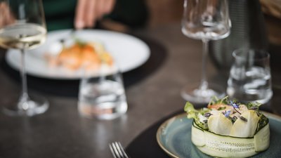 Insalata ben presentata su un piatto con bicchiere di vino e acqua sullo sfondo
