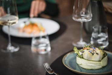 Elegantly plated salad on a dish with wine glass and water glass in background