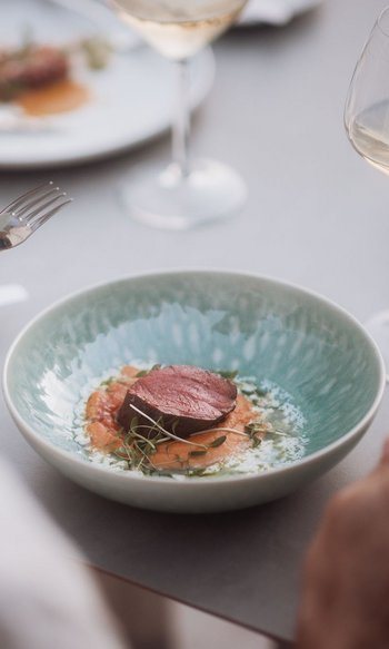 Persona che mangia un pezzo di carne su verdure con vino al ristorante
