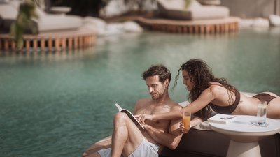 Photos from your hotel in Pfalzen in Val Pusteria/Pustertal Couple relaxing by pool reading a book and drinking juice