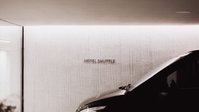 Schwarzes Auto parkt vor Wand mit Schrift Hotel Shuttle