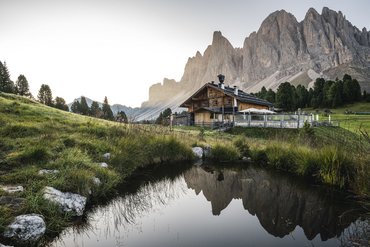 Almhütte vor Bergkulisse mit Spiegelung im Teich