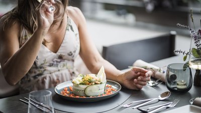 Frau trinkt Wein und isst ein dekoratives Gericht im Restaurant