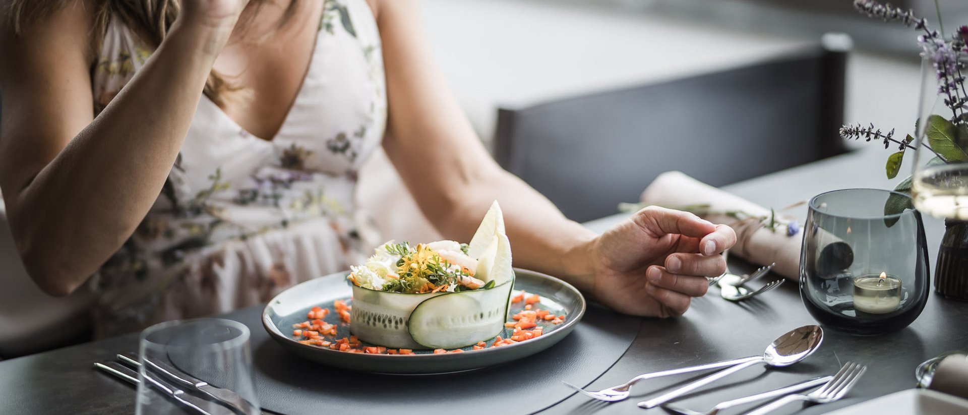 Donna che beve vino e mangia un piatto decorativo al ristorante