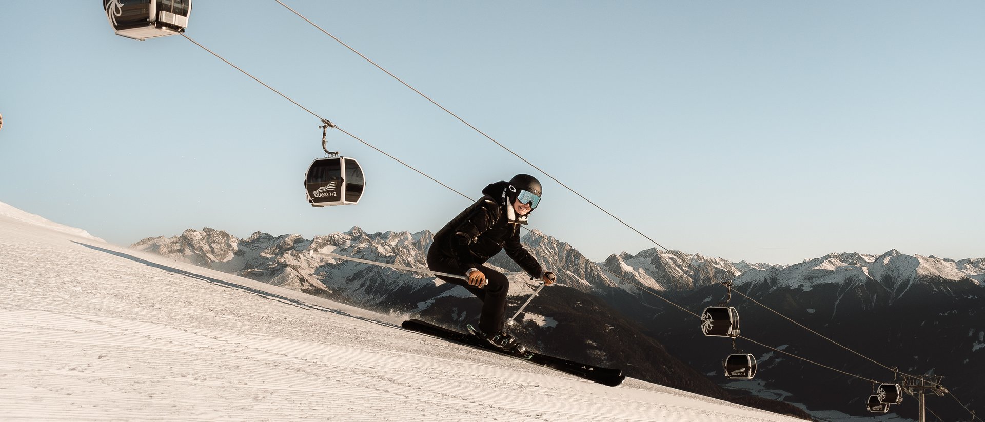 Hotel sulle piste del Plan de Corones: divertimento senza fine Sciatore su pista innevata con seggiovia e montagne sullo sfondo