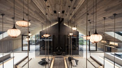 Soggiorno moderno con soffitto in legno, lampade sospese e camino centrale