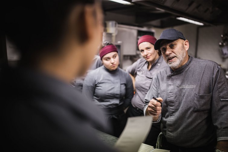 Koch erklärt Küchenpersonal eine Bestellung im Restaurant