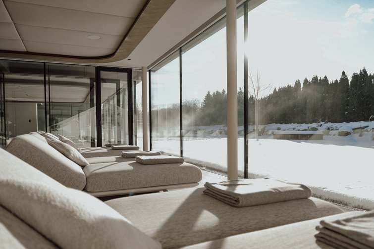 Lounge chairs with towels by large window overlooking snowy landscape