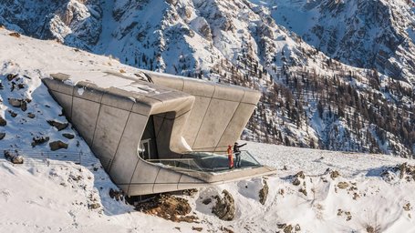 Modern mountain station in snowy Alpine landscape with two people on observation deck