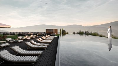 Lettini vuoti vicino a piscina a sfioro con persona in accappatoio