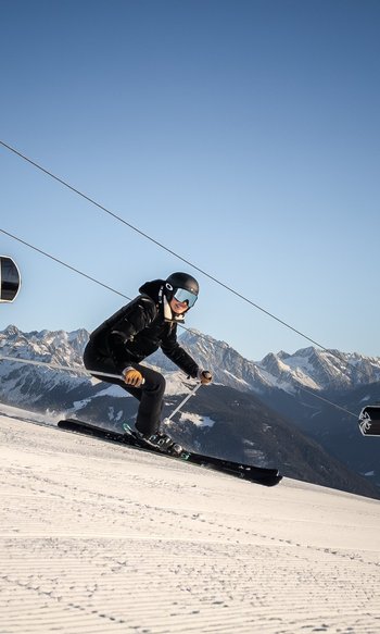Sciatore scende una pista con funivia e montagne innevate sullo sfondo