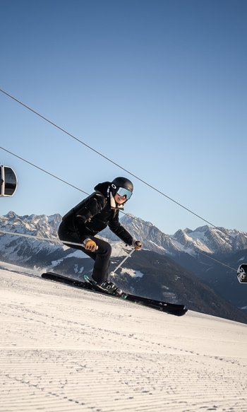 Sciatore scende una pista con funivia e montagne innevate sullo sfondo
