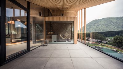 L’esclusività in foto: il nostro chalet in Alto Adige di lusso Balcone moderno con grandi finestre in vetro e vista sulle colline boscose