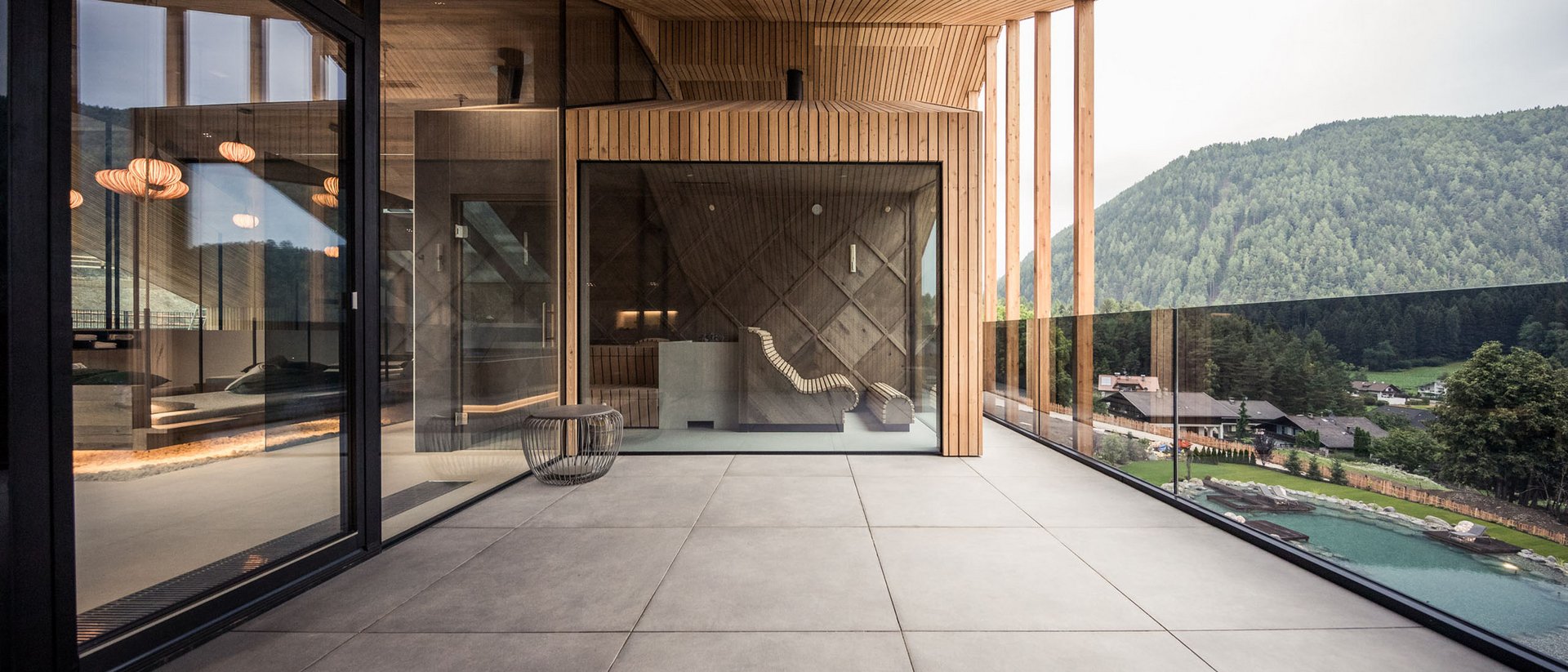 Moderner Balkon mit großem Glasfenster und Blick auf bewaldeten Hügel