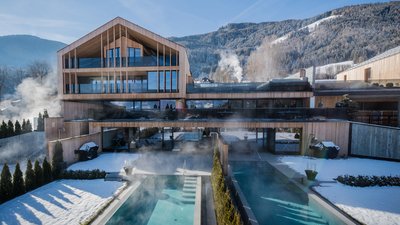 Casa moderna in legno con piscina riscaldata all'aperto e paesaggio montano innevato