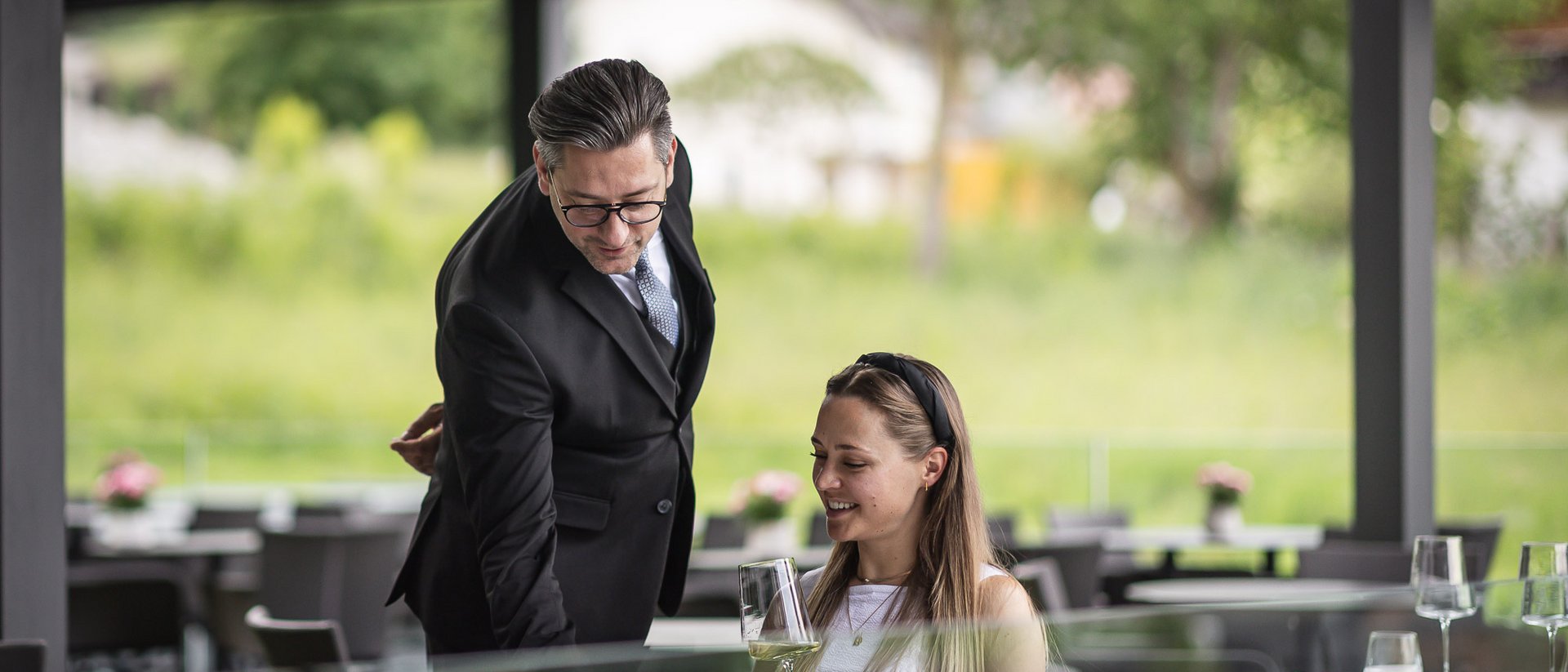 Cameriere serve una donna con vino in un ristorante all'aperto