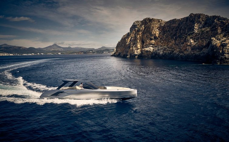 Lusso yacht che naviga velocemente vicino a costa rocciosa su mare calmo