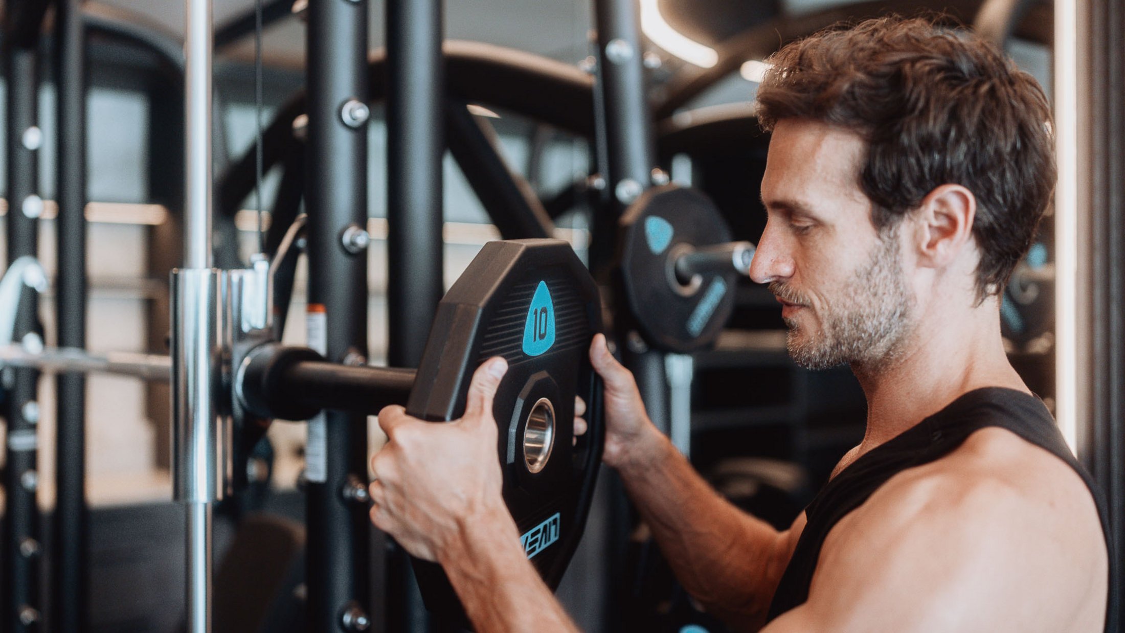 Mann montiert Gewichtsscheibe im Fitnessstudio