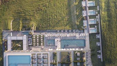Vista aerea di un edificio moderno con diverse piscine vicino a un campo verde