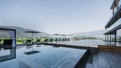 Piscina all'aperto moderna con lettini e vista sulle montagne sotto un cielo chiaro
