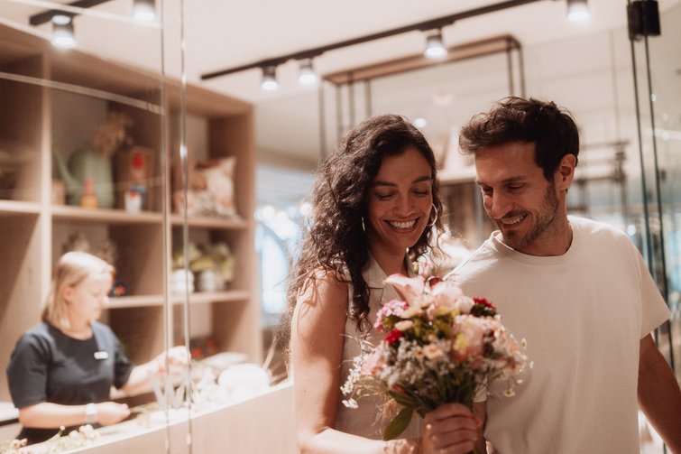 Una coppia sorride guardando un bouquet di fiori in un negozio di fiori