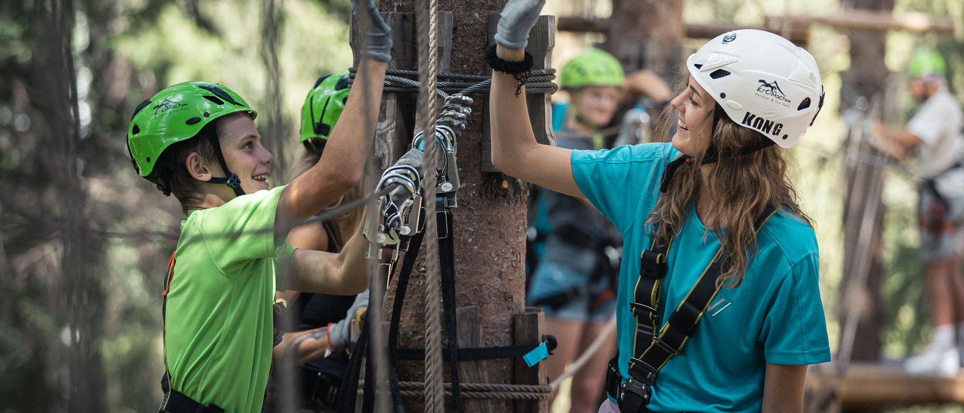Junge und Mädchen beim Klettern im Hochseilgarten geben sich High Five