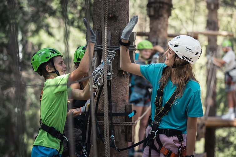 Boy and girl giving high five while climbing in an adventure park