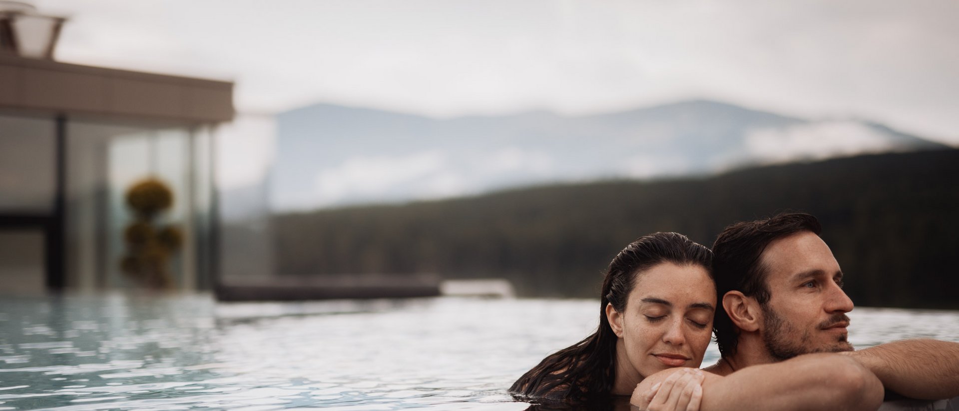 Paar entspannt im Pool mit Bergblick im Hintergrund