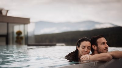 Photos from your hotel in Pfalzen in Val Pusteria/Pustertal Couple relaxing in pool with mountain view in background