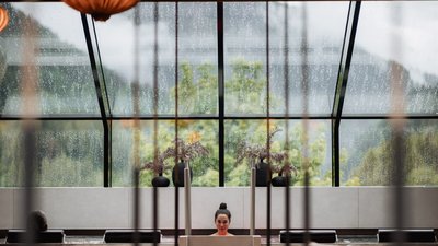 L’esclusività in foto: il nostro chalet in Alto Adige di lusso Donna si rilassa nella piscina coperta con tetto di vetro sotto la pioggia