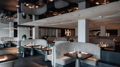 Modern restaurant with gray upholstered seats and set tables