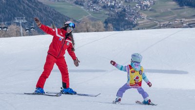 Skilehrerin unterrichtet Kind im Skifahren auf schneebedecktem Hang