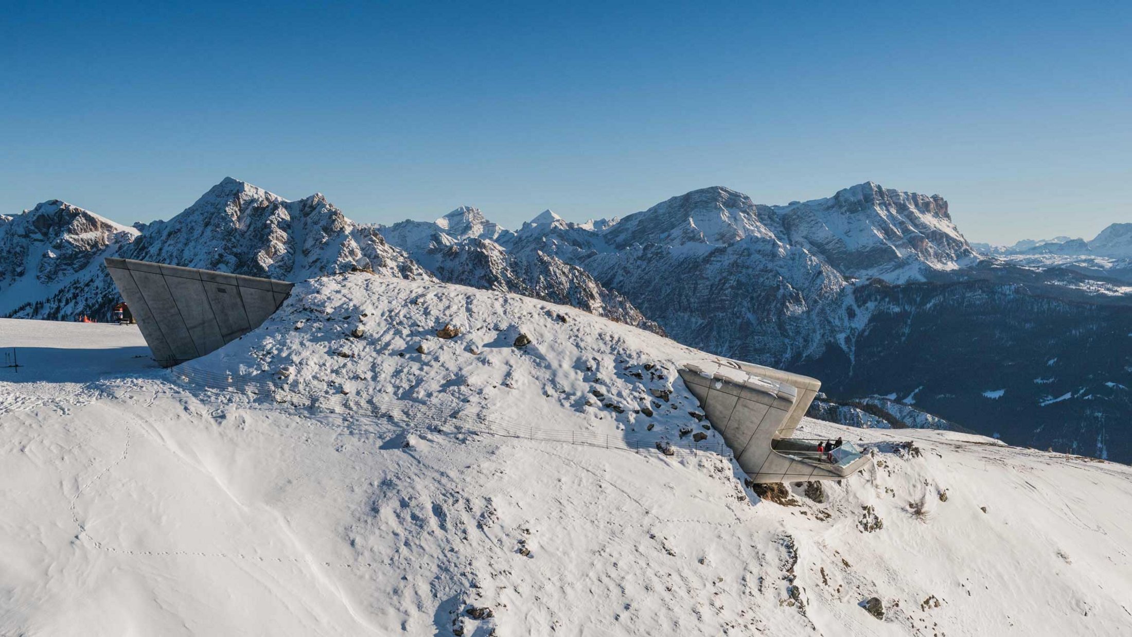 Moderne Aussichtsplattform auf verschneitem Berg mit Alpen im Hintergrund