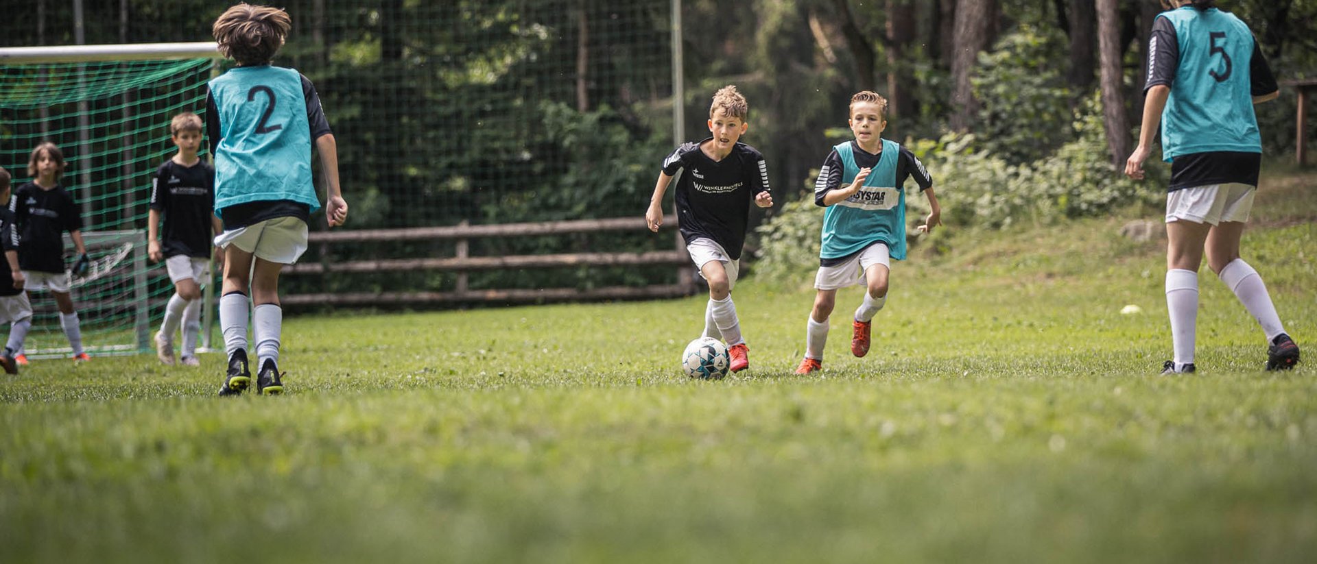 Bambini che giocano a calcio su un campo all'aperto verde