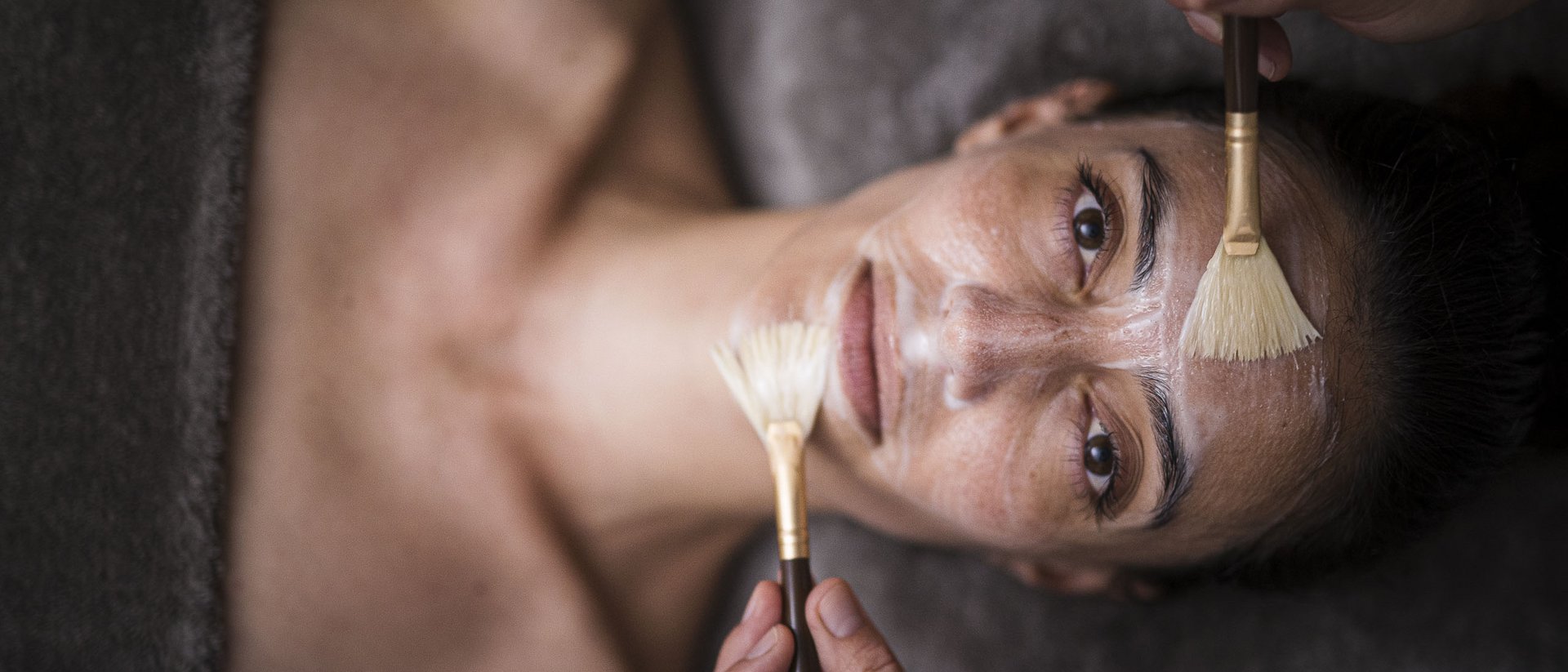 Donna riceve una maschera viso applicata con pennelli in una spa